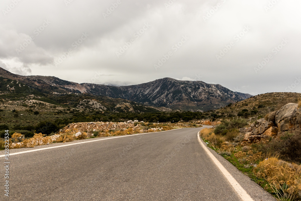A cloudy day in the countryside of Crete. A road leading to the mountains
