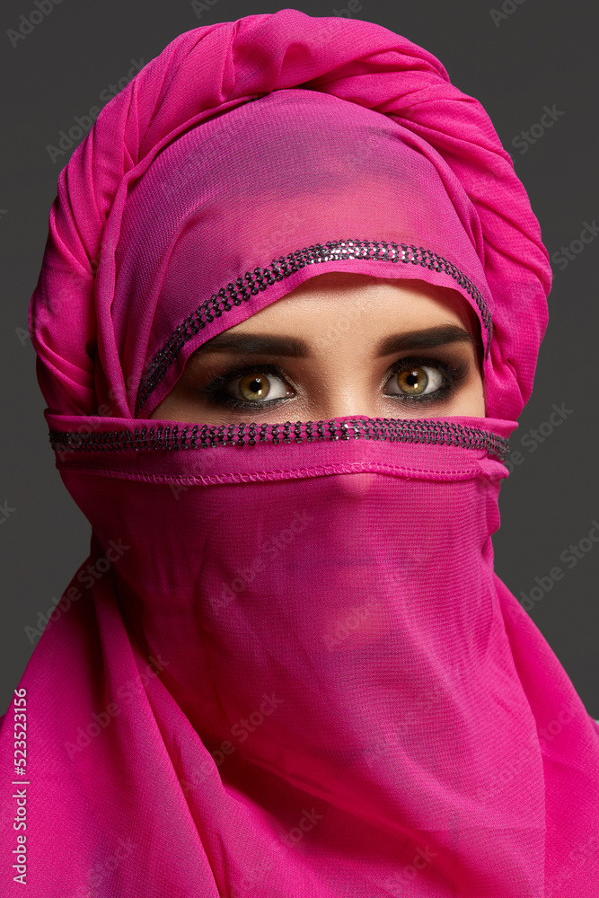 Close-up shot of a young charming woman wearing the pink hijab decorated with sequins. Arabic style. Close-up shot of a young charming woman wearing the pink hijab decorated with sequins. Arabic style.
