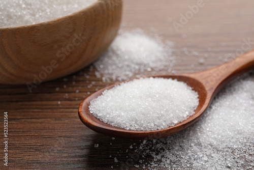 Granulated sugar on wooden table, closeup view