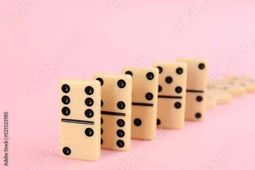 White domino tiles falling on pink background