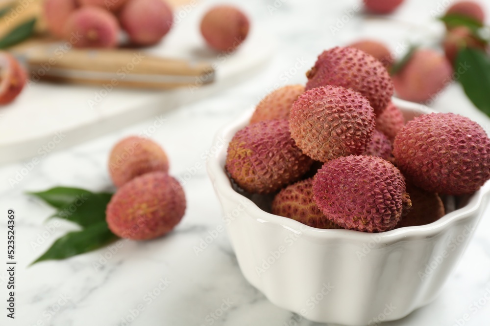 Fresh ripe lychee fruits in ceramic bowl on white marble table. Space for text Fresh ripe lychee fruits in ceramic bowl on white marble table. Space for text