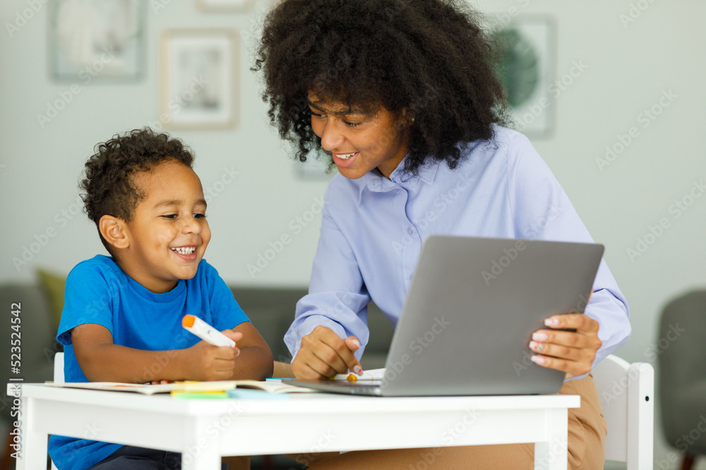 Portrait of cute african boy in using laptop with teacher, learning Portrait of cute african boy in using laptop with teacher, learning