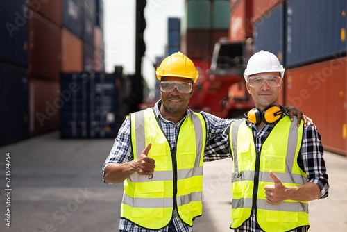 Portrait of Caucasian businessman with African worker in container port. Attractive male engineer people working and processes order at warehouse logistic in cargo freight ship import export in harbor © Boonkung