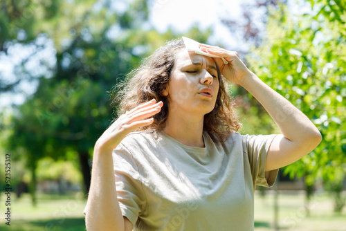 Young woman having hot flash and sweating in a warm summer day.