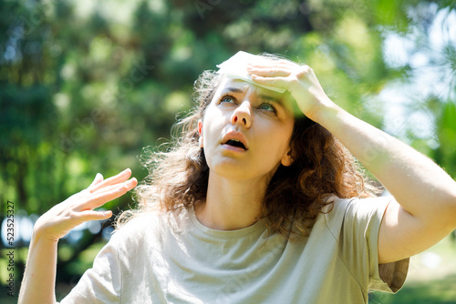 Young woman having hot flash and sweating in a warm summer day.