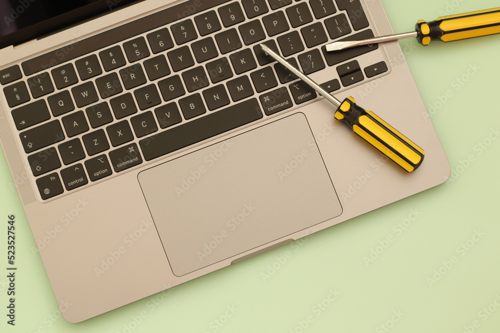 computer repair, laptop and yellow screwdrivers on green background computer repair, laptop and yellow screwdrivers on green background