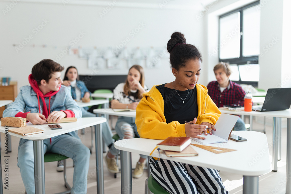 High school students paying attention in class, sitting in their desks and writing notes, back to school concept. High school students paying attention in class, sitting in their desks and writing notes, back to school concept.