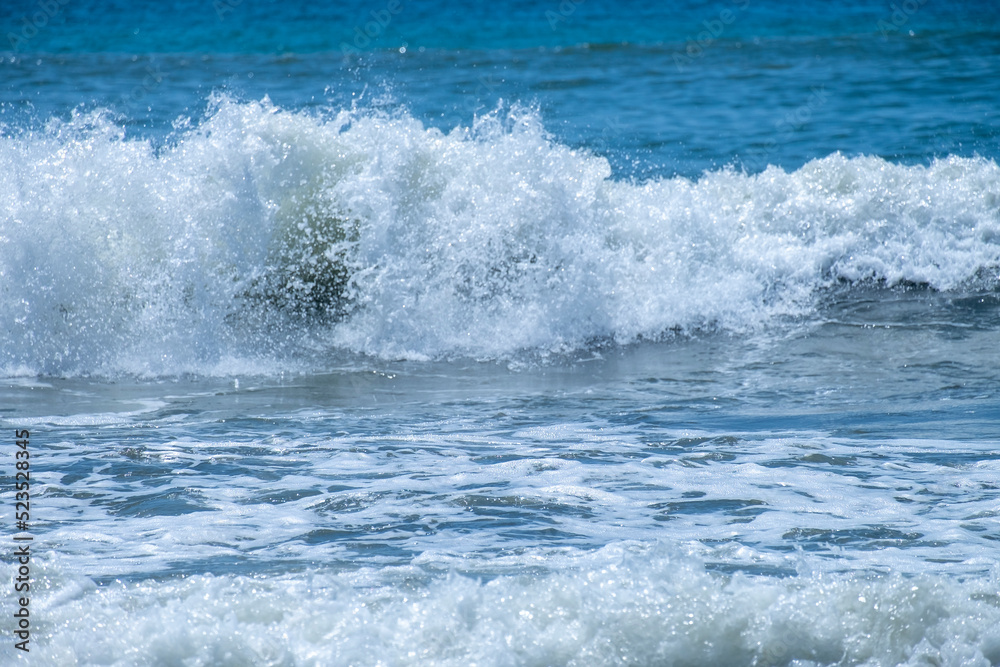 Ocean waves crashing on sandy beach. Sea waves breaking on Maditerranean's shore.