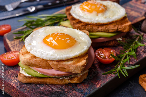 Fresh, delicious sandwiches with fried egg, ham, butter, avocado and sesame seeds