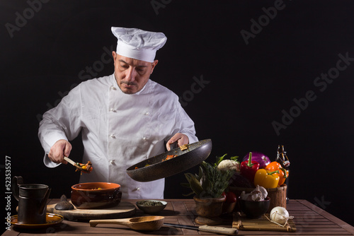 Male chef in white uniform preparing food plate with vegetables