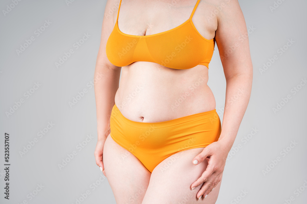 Foto Stock Fat woman in orange underwear on gray background, overweight  female body | Adobe Stock