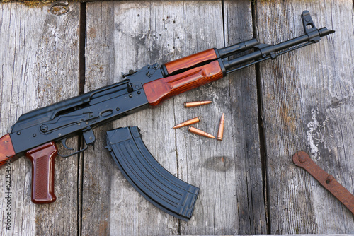 The famous Kalashnikov assault rifle with magazine and cartridges on an old, damaged board photo