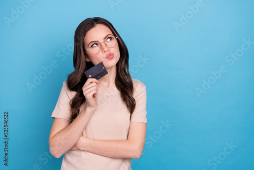 Photo of minded lady hold credit card decide plan paying buyings purchase order isolated blue color background