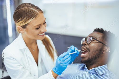 Young african-american man visiting dentist s office for prevention and treatment of the oral cavity. Man and male doctor while checkup teeth. Healthy lifestyle  healthcare and medicine concept.