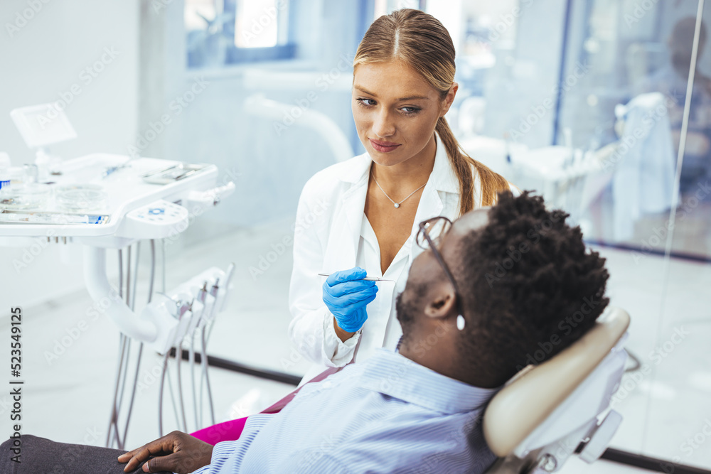 Female dentist with happy male patient at clinic. Happy patient sitting