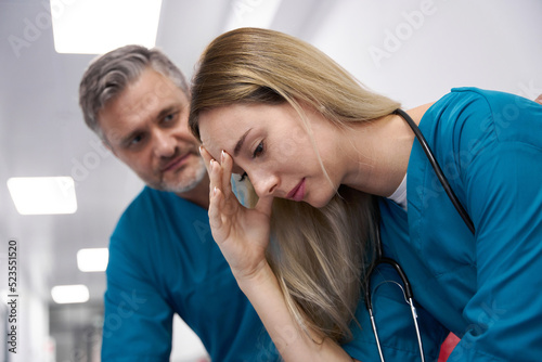 Old doctor comforting doctor woman in hospital corridor