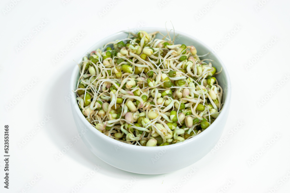 Bowl of sprouted mung beans (Vigna radiata) with small roots for eating. White background. Close up.