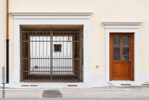 Porta di entrata di casa e passo carrabile su facciata gialla  di edificio ristrutturato. Centro storico di piccola città.