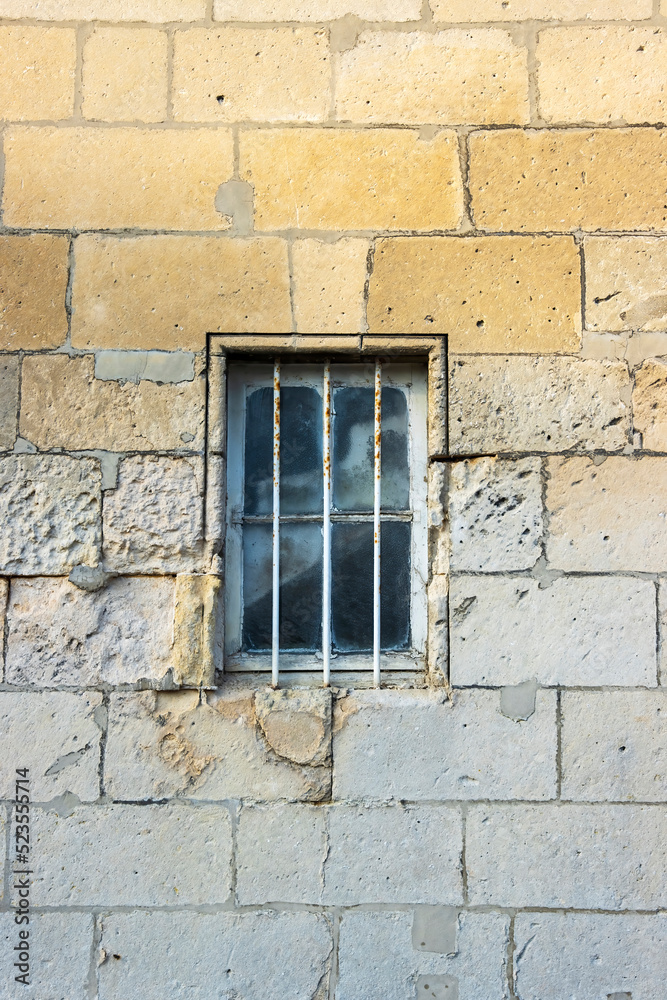 Security bars on a window in a beautiful textures natural stone wall.