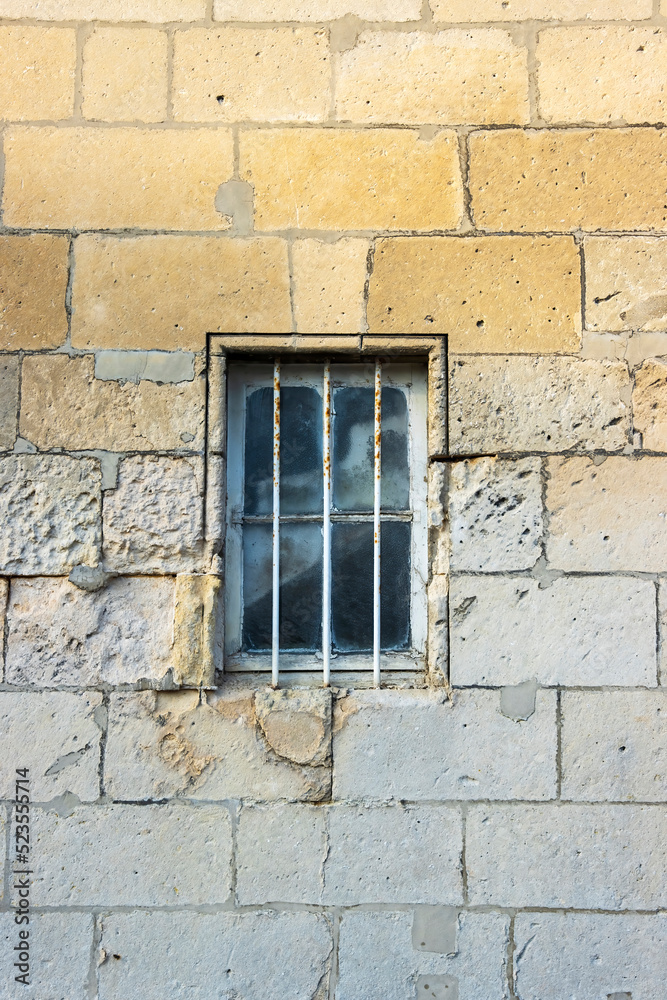 Security bars on a window in a beautiful textures natural stone wall. Security bars on a window in a beautiful textures natural stone wall.