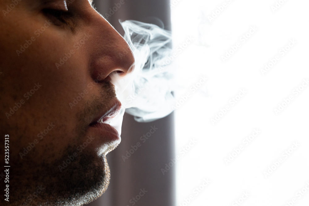 Male lips blowing smoke close-up, cigarette smoke and lips on black background. Male lips blowing smoke close-up, cigarette smoke and lips on black background.