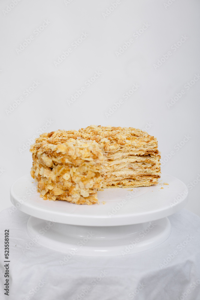 Napoleon cake in a cut on a white tray isolated on a white background. Cake of puff pastry with sour cream. Copy space. Napoleon cake in a cut on a white tray isolated on a white background. Cake of puff pastry with sour cream. Copy space.