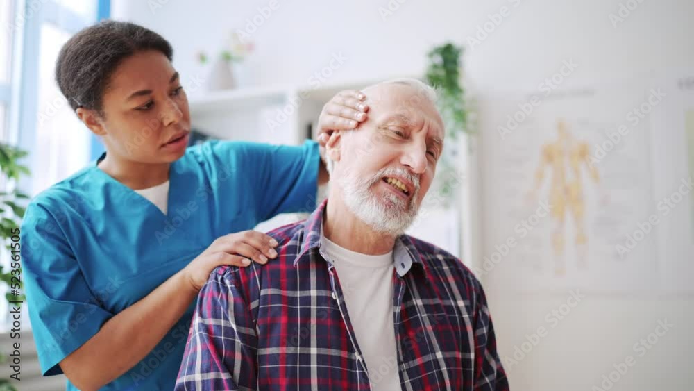 Man in his 60s feeling neck pain during examination in clinic, muscle spasms