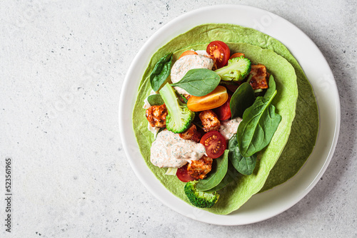 Open vegan tortilla wrap with broccoli, tofu and tomatoes. Vegetarian recipe, comfort food, plant-based concept.