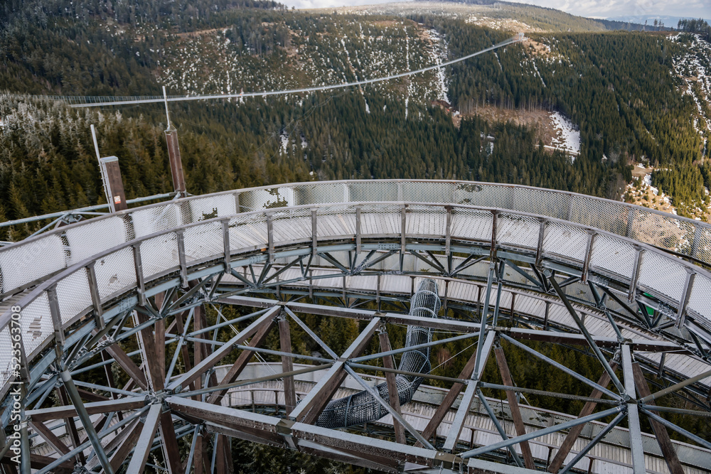 Dolni Morava, Czech Republic, 16 April 2022: Path in the clouds, tourist attraction with spiral platform to observation tower, landscape with forest and sky on mountains, Skywalk with snow