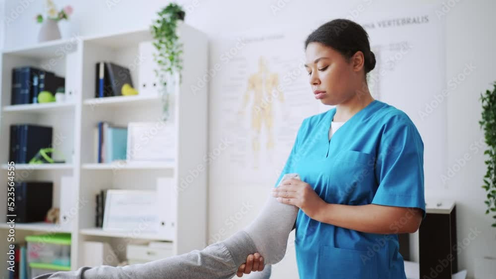 Female orthopedist examining foot of her patient in office, medical consultation Female orthopedist examining foot of her patient in office, medical consultation