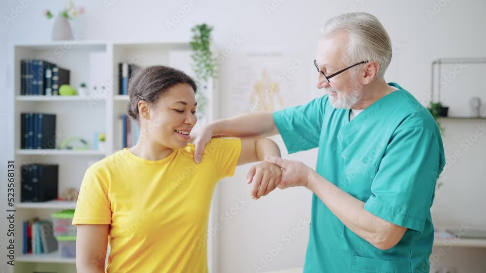 Male orthopedist examining patient's shoulder in clinic, recovery from injury Male orthopedist examining patient's shoulder in clinic, recovery from injury