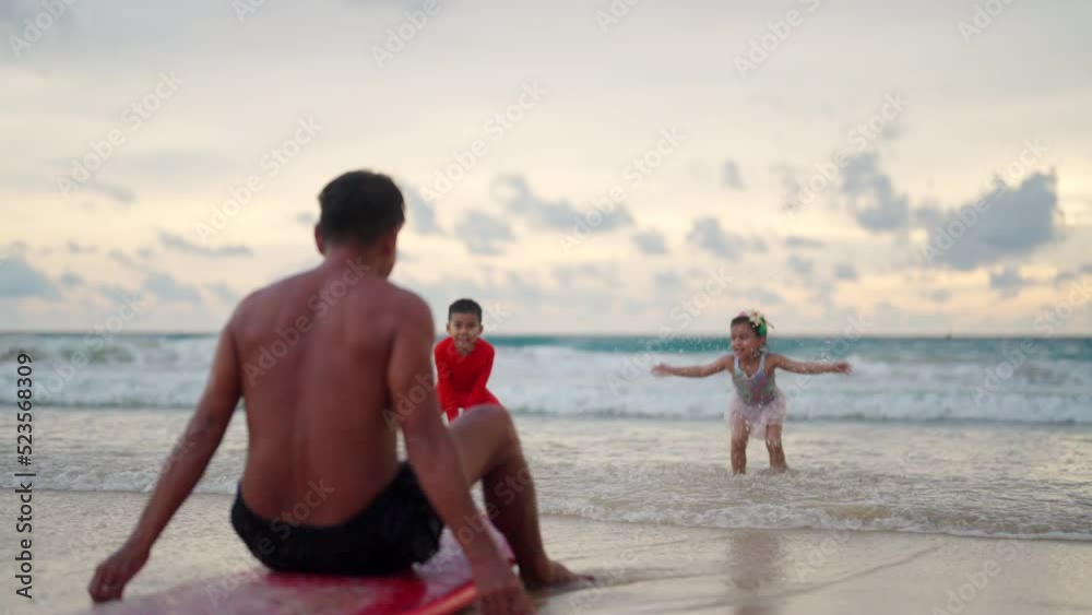 Happy Asian family on summer travel vacation. Grandfather with grandchild boy and girl enjoy and fun outdoor activity lifestyle relaxing and playing together after surfing on tropical beach at sunset. Happy Asian family on summer travel vacation. Grandfather with grandchild boy and girl enjoy and fun outdoor activity lifestyle relaxing and playing together after surfing on tropical beach at sunset.