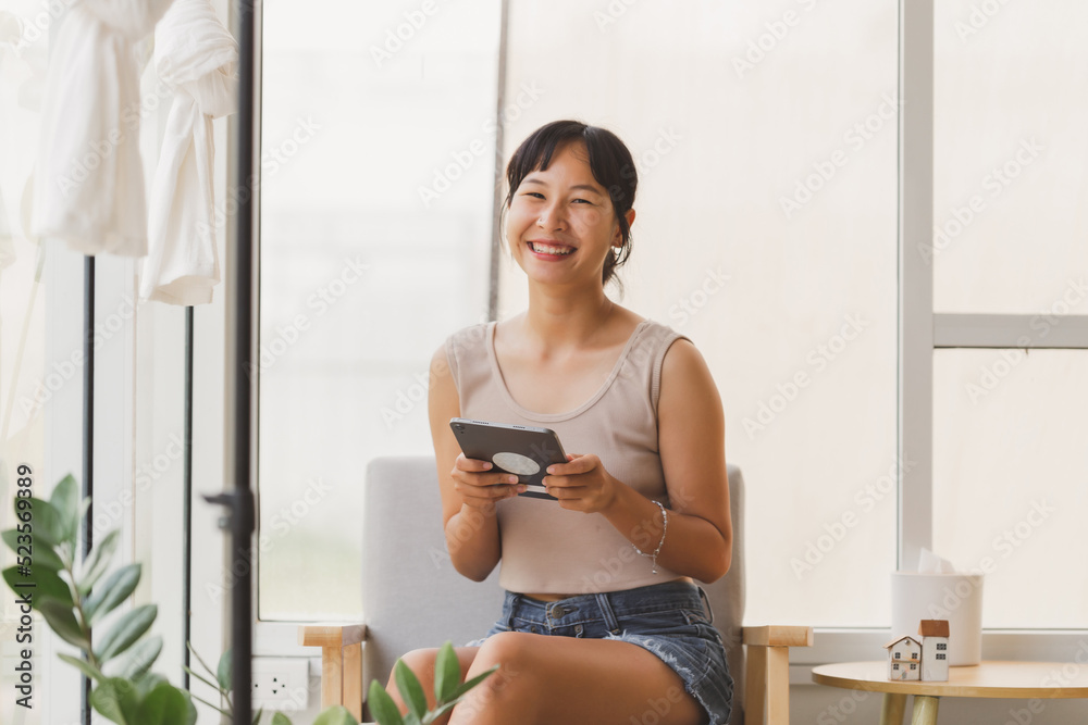 Portrait of young attractive cheerful Asian woman holding digital tablet looking at camera with smiley face. Happy smile freelance teenager using tablet with internet for the business Portrait of young attractive cheerful Asian woman holding digital tablet looking at camera with smiley face. Happy smile freelance teenager using tablet with internet for the business