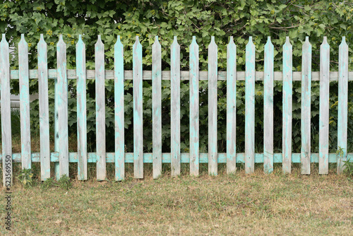 a small blue wooden fence stands against the background of a high red metal fence