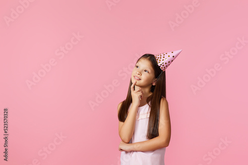 happy little girl with party cone making wish on her birthday