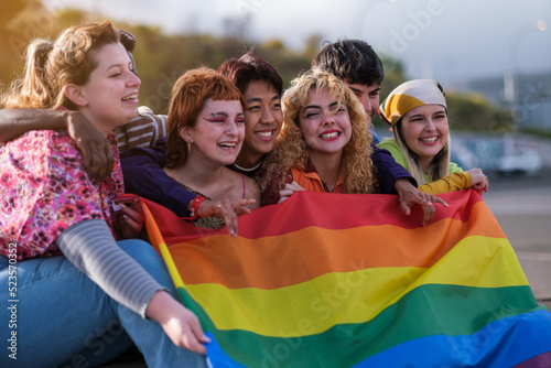 Group of young people from different cultures holding the lgtbi flag to fight for pride