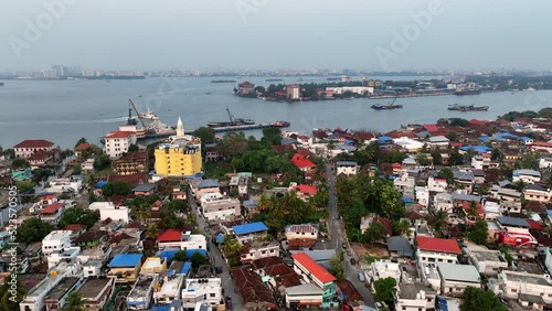 Aerial Panning Shot Of Residential Houses In City By Rippled Lake Against Clear Sky - Kochi, India photo