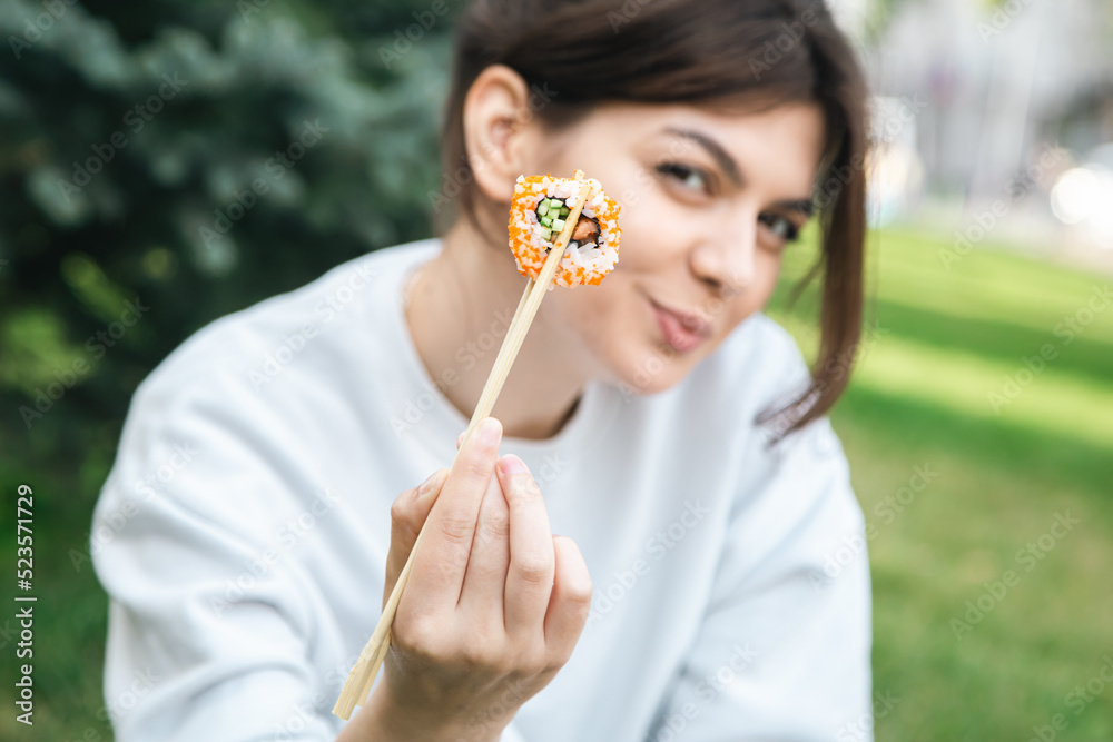 A young woman eating sushi in the park, picnic in nature. A young woman eating sushi in the park, picnic in nature.