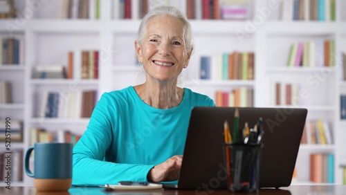 Portrait of elderly senior older woman on laptop looks up and smiles online concept, watching business training class, live webinar on laptop computer remote working, distance learning, home office.
