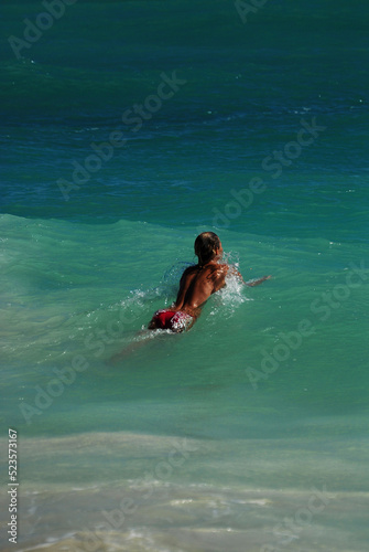 A young topless woman swims in the Caribbean Sea on a sunny day during her summer vacation in Mexico