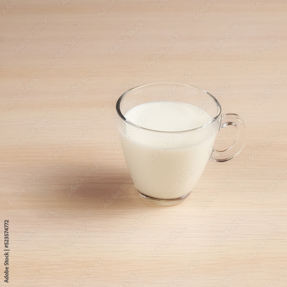 Transparent cup with milk on a wooden table. Delicious Drink