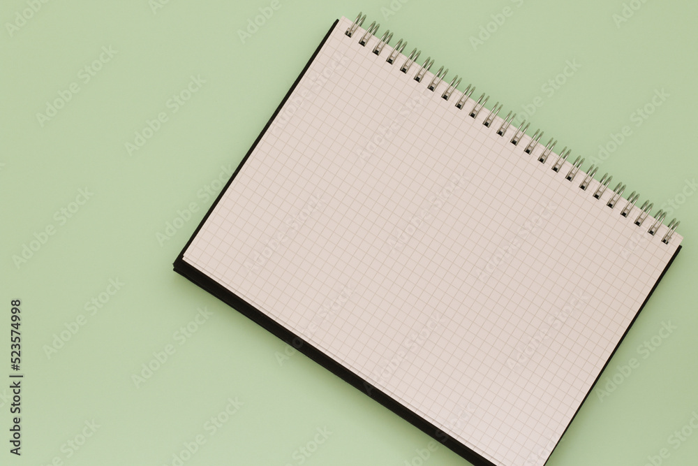 blank checkered notebook with spiral on green background