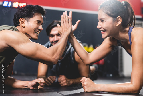 woman and man friends high fiving exercise while planking on a fitness gym floor  happy lifestyle to fit training together with teamwork for slim and healthy strength body by active sport
