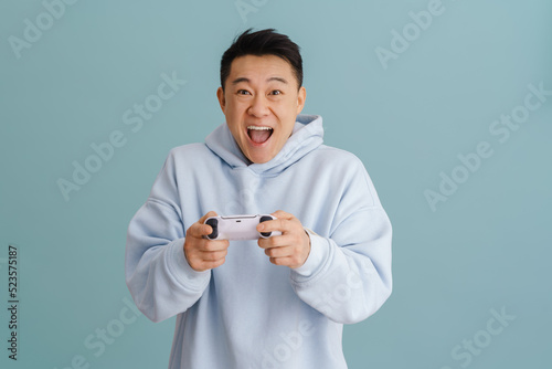 Asian excited man screaming while playing video game with joystick