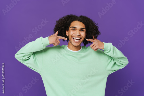 Young caribbean man with piercing pointing fingers at his smile