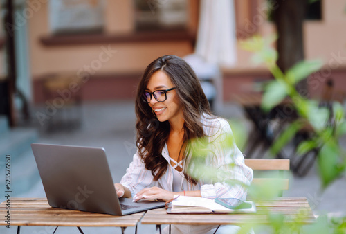 Smiling woman sitting in the cafe and working on laptop. Freelancer, business, online, education concept.
