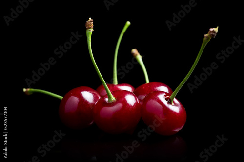 Red cherry berries on a black background with mirror. Three cherries