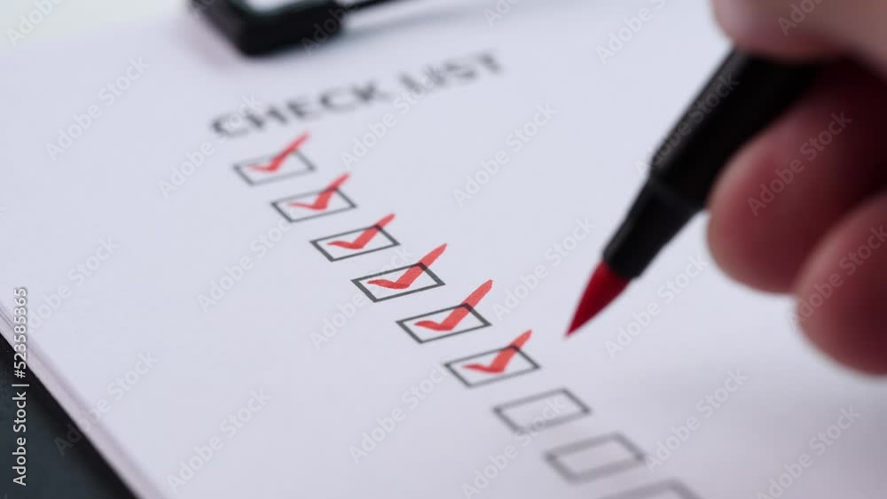 Checklist and To Do List Concept. After finishing a job on white paper, a close-up businessman ticks off or marks it with red mark on checklist, checkbox, to-do list box. selective focus 4K