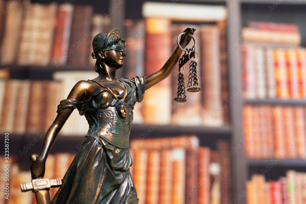 Fototapeta premium Lawyer office. Statue of Justice with scales close-up against the backdrop of a wall of books or a library . Legal law, advice and justice concept