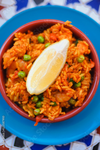 Arroz rojo, a traditional Spanish rice dish also called Mexican Red Rice made of  rice, tomatoes, green peas served in tapas bowl with lemon wegde in a Spain bodega bar photo